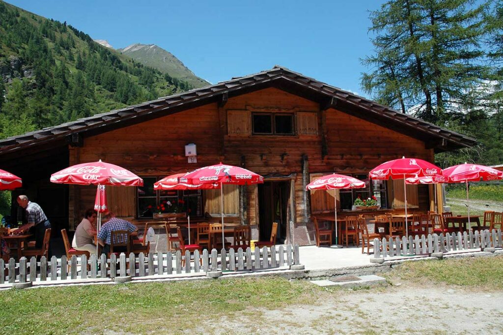 Die urige Holzütte der Bergeralm mit roten Sonnenschirmen davor