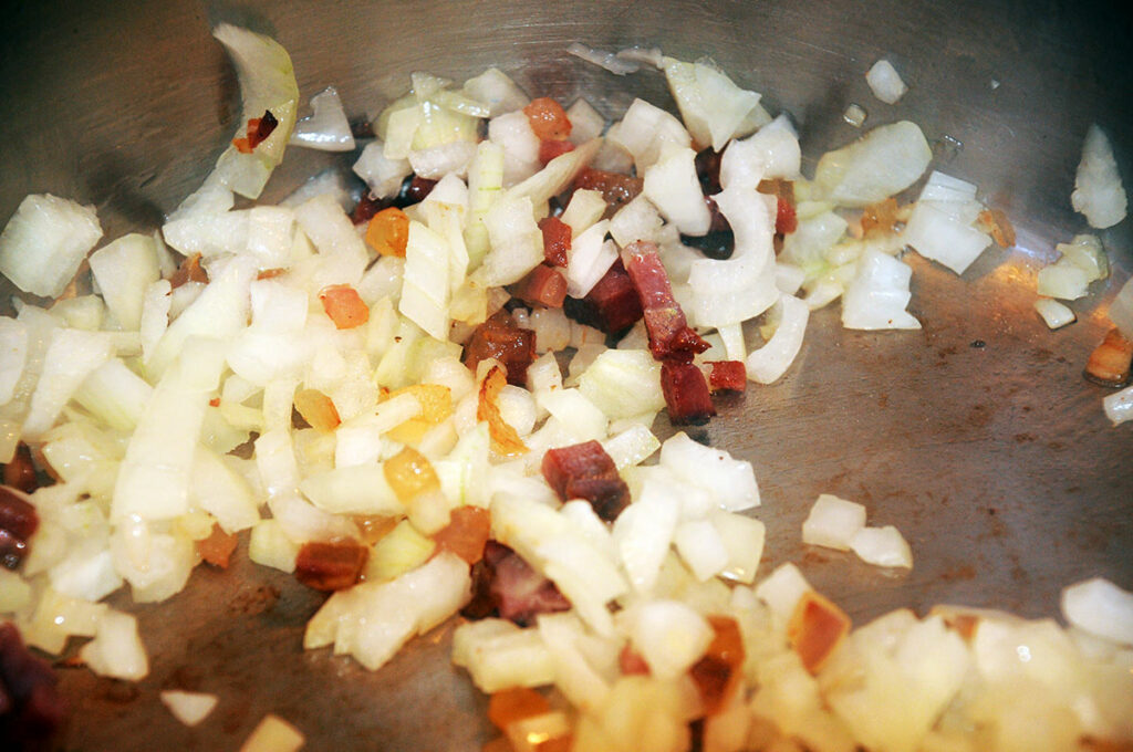 Speck auslassen und mit Zwiebel anrösten.
