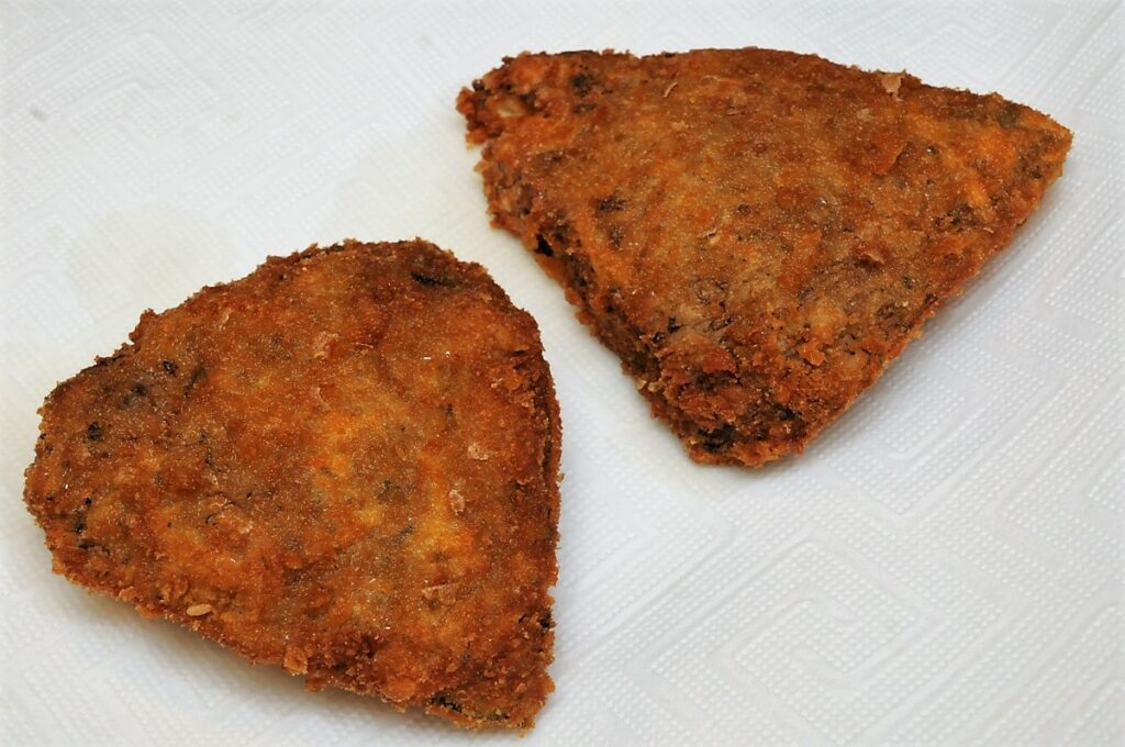 Panierte Pilze auf einem Stück Küchenrolle abtropfen lassen