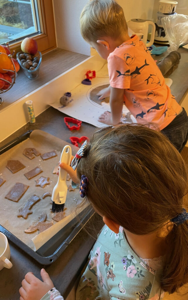 Kinder backen Lebkuchenkekse Lebkuchenhäuschen mit Milch bepinseln Batmanausstecher