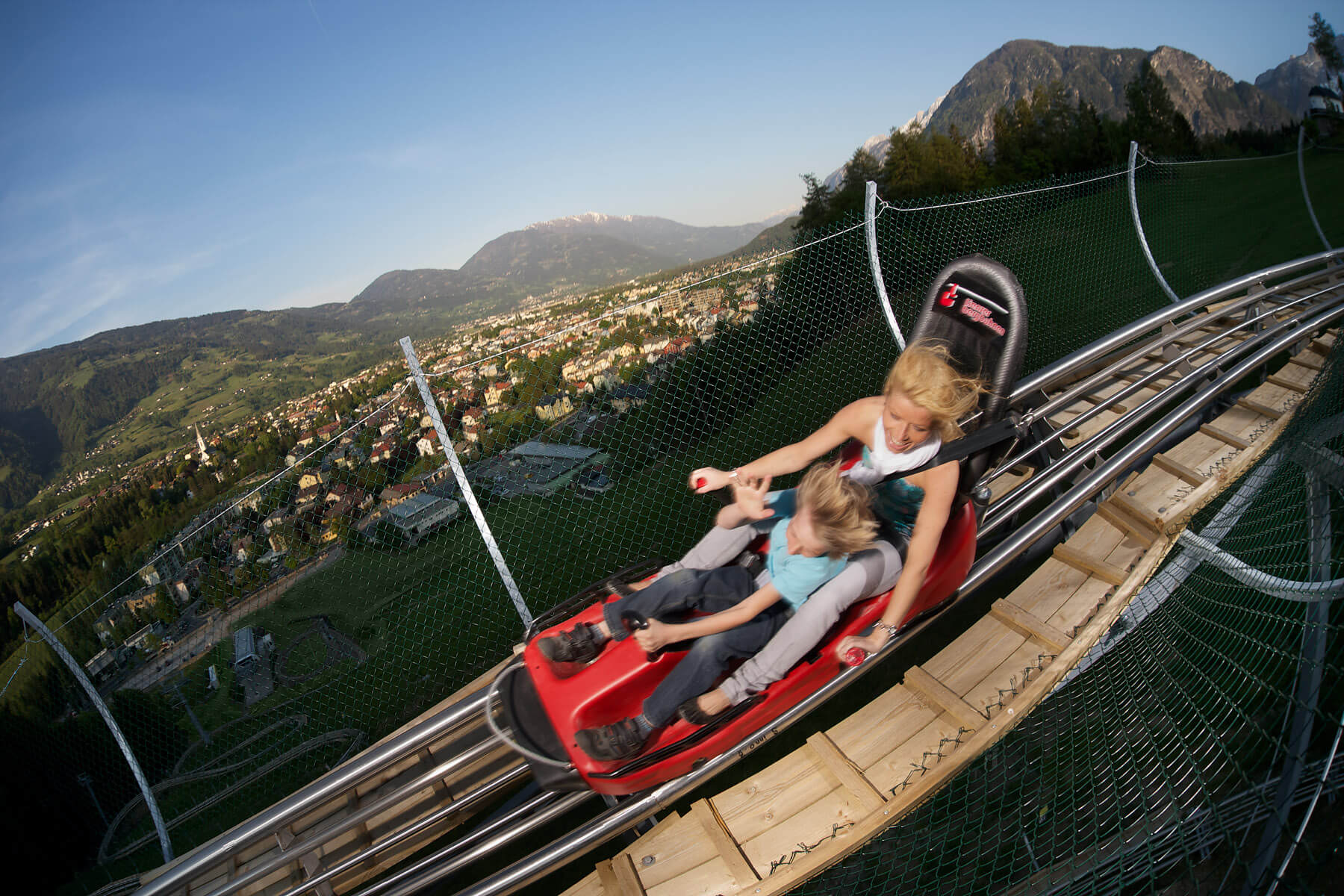 Sommerrodelbahn Ausblick Mutter Kind Berge Stadt