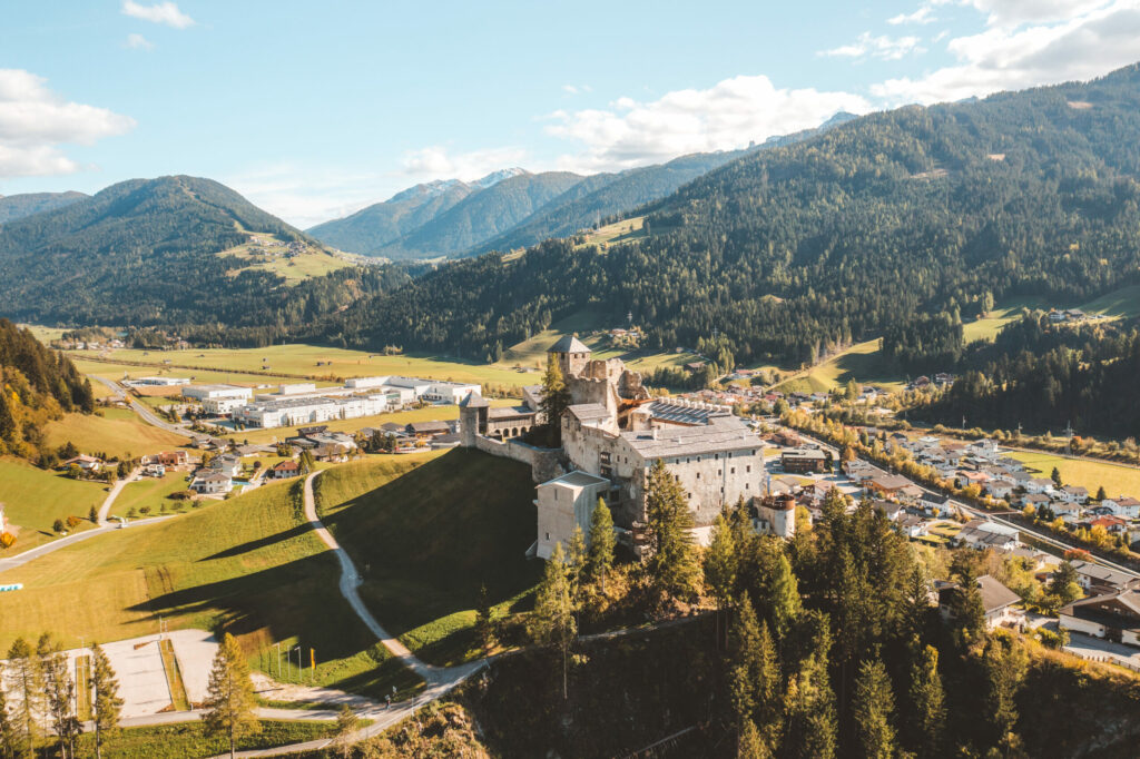 Blick von oben auf die Burg Heinfels an einem Sommertag mit strahlend blauem Himmel.