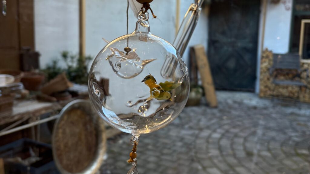 Handgefertigte Glaskugel von GlasGrün mit einem kunstvoll gestalteten grünen Vogel im Inneren.