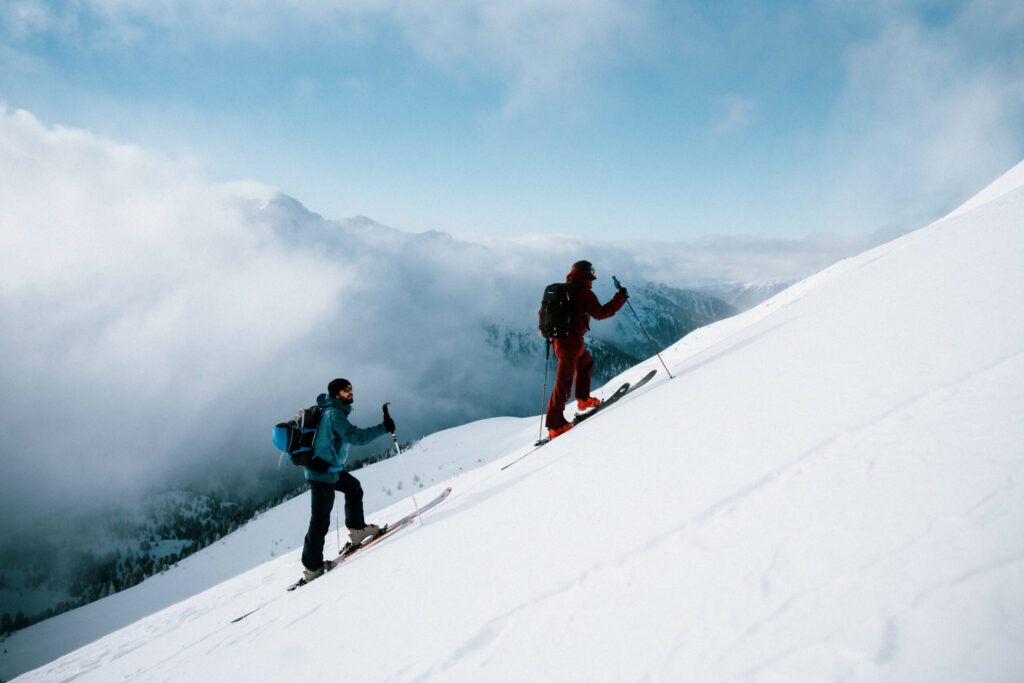 Zwei Personen sind auf einer Skitour zur Roten Wand im Defereggental. Die Sonne scheint durch die Nebelschwaden hintdurch.