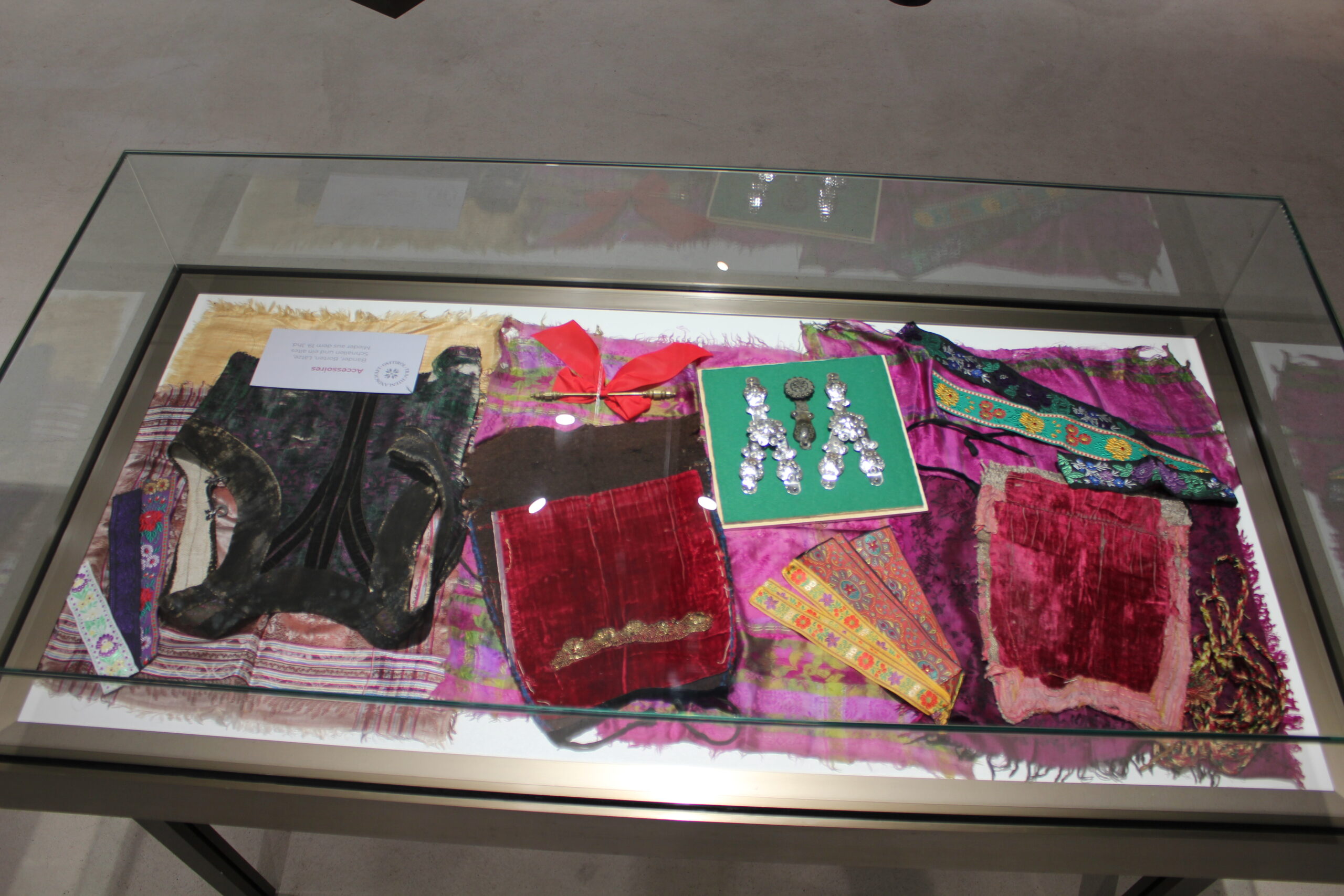 Bis heute wird bei den traditionellen Gewändern großer Wert auf hochwertige Materialien und stilvolle Accessoires gelegt. Hier zu sehen sind verschiedene Stoffe, Bänder und Stickerein sowie Anstecker für die Iseltaler Tracht.