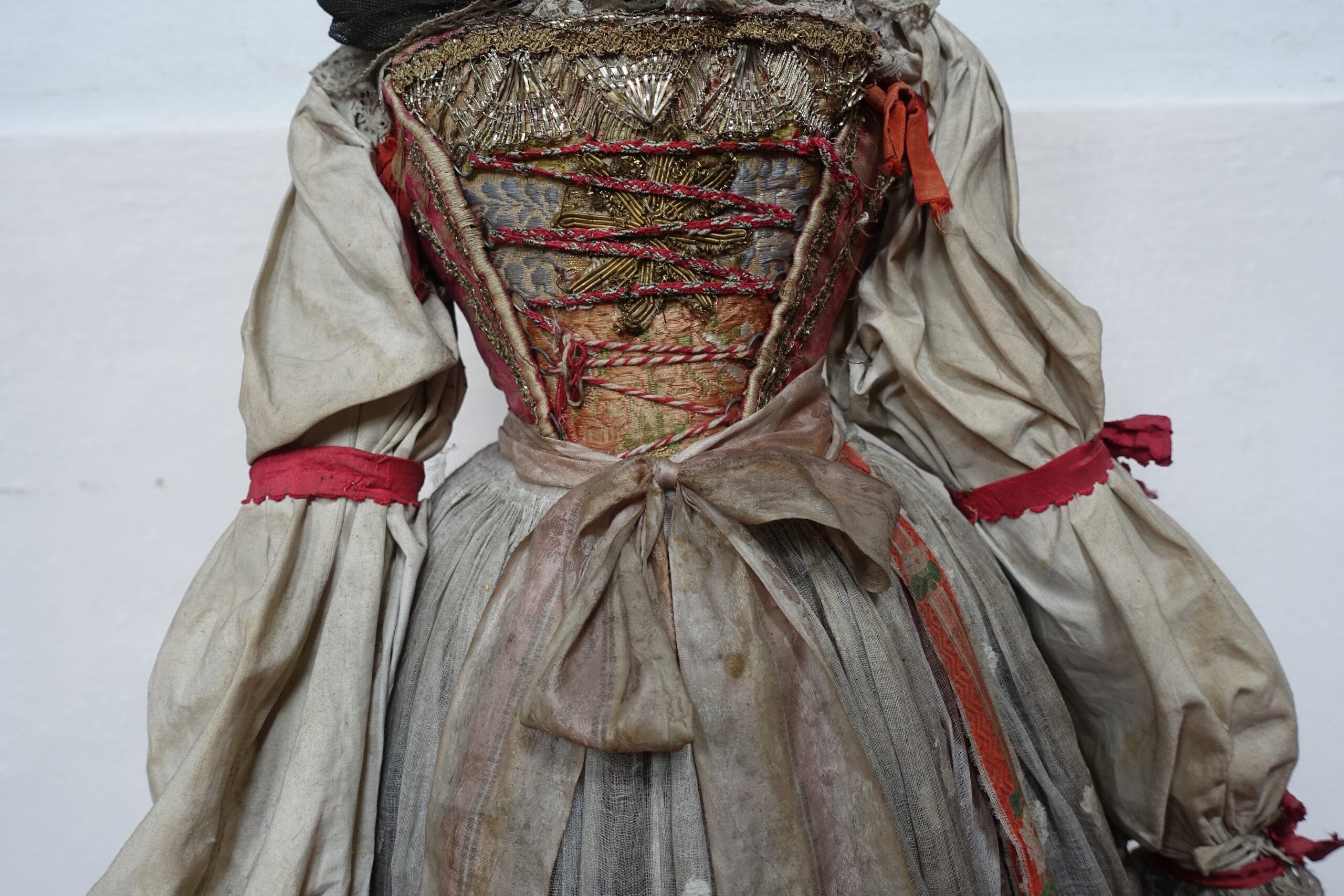 Die Tracht der heiligen Notburga stammt laut dem Tiroler Volkskunstmuseum aus dem Jahr 1840. Sie zeichnet sisch durch hellgraue Stoffe und Rote Akzente aus.