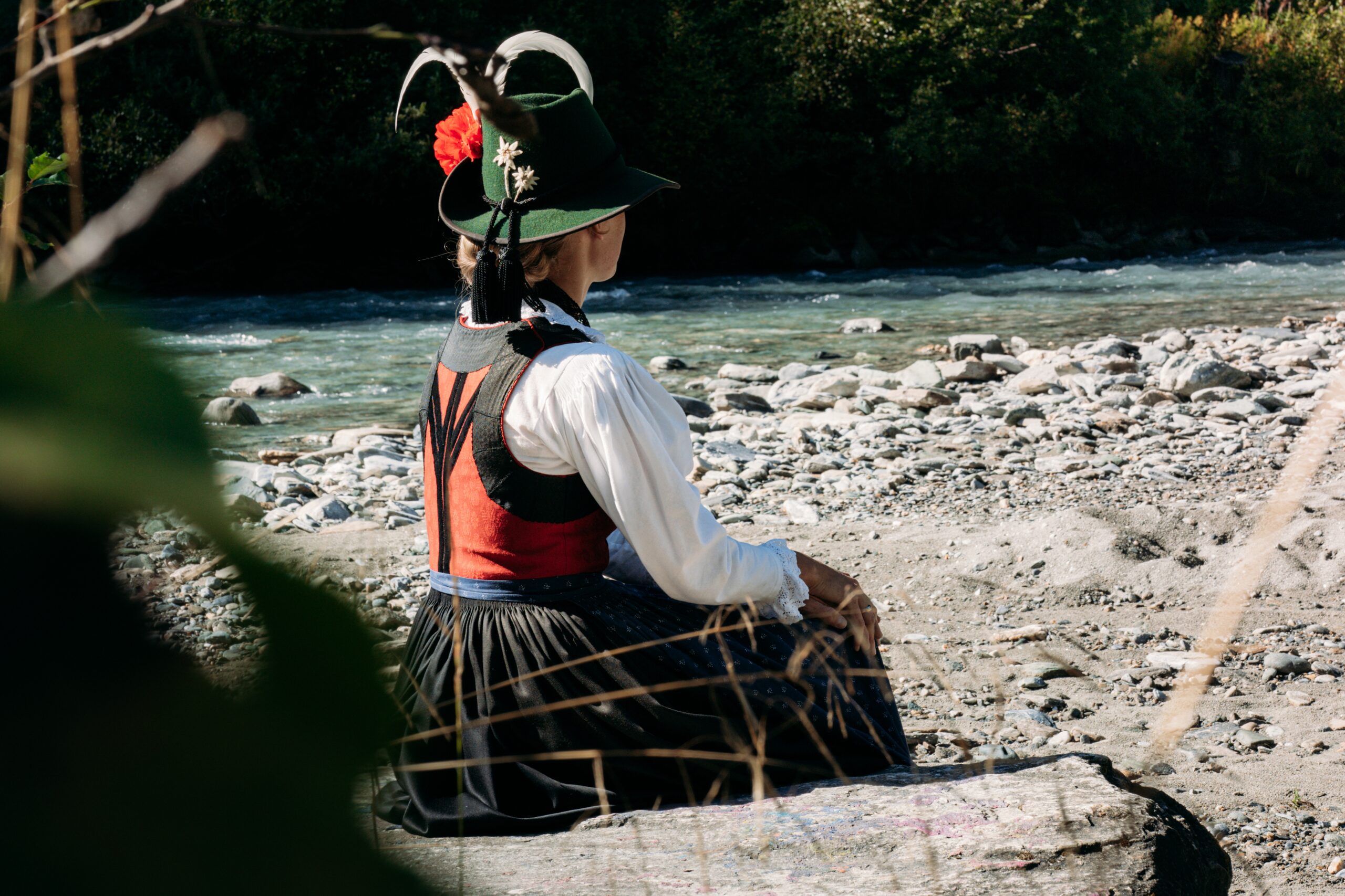 Die obere Latzkante, der Rücken und die Ärmelausschnitte sind mit schwarzem Trachtenband eingefasst.