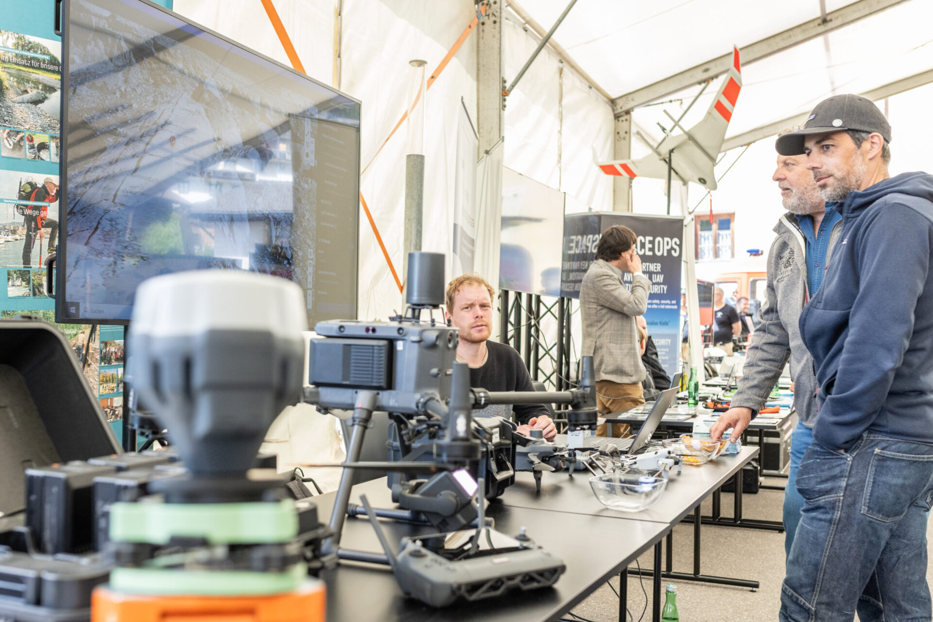 Zwei Herren stehen an einem Ausstellungsstand auf dem Festival und begutachten die Drohnen.