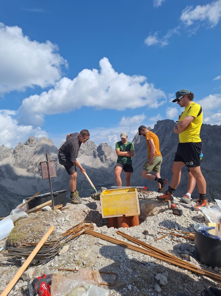 Mehrere Personen arbeiten am Fundament für das neue Gipfelkreuz.