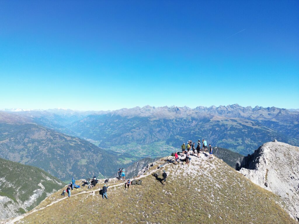 Blick von oben Richtung Gipfel der Gamswiesenspitze. Viele Personen befinden sich dort oben am Arbeiten.