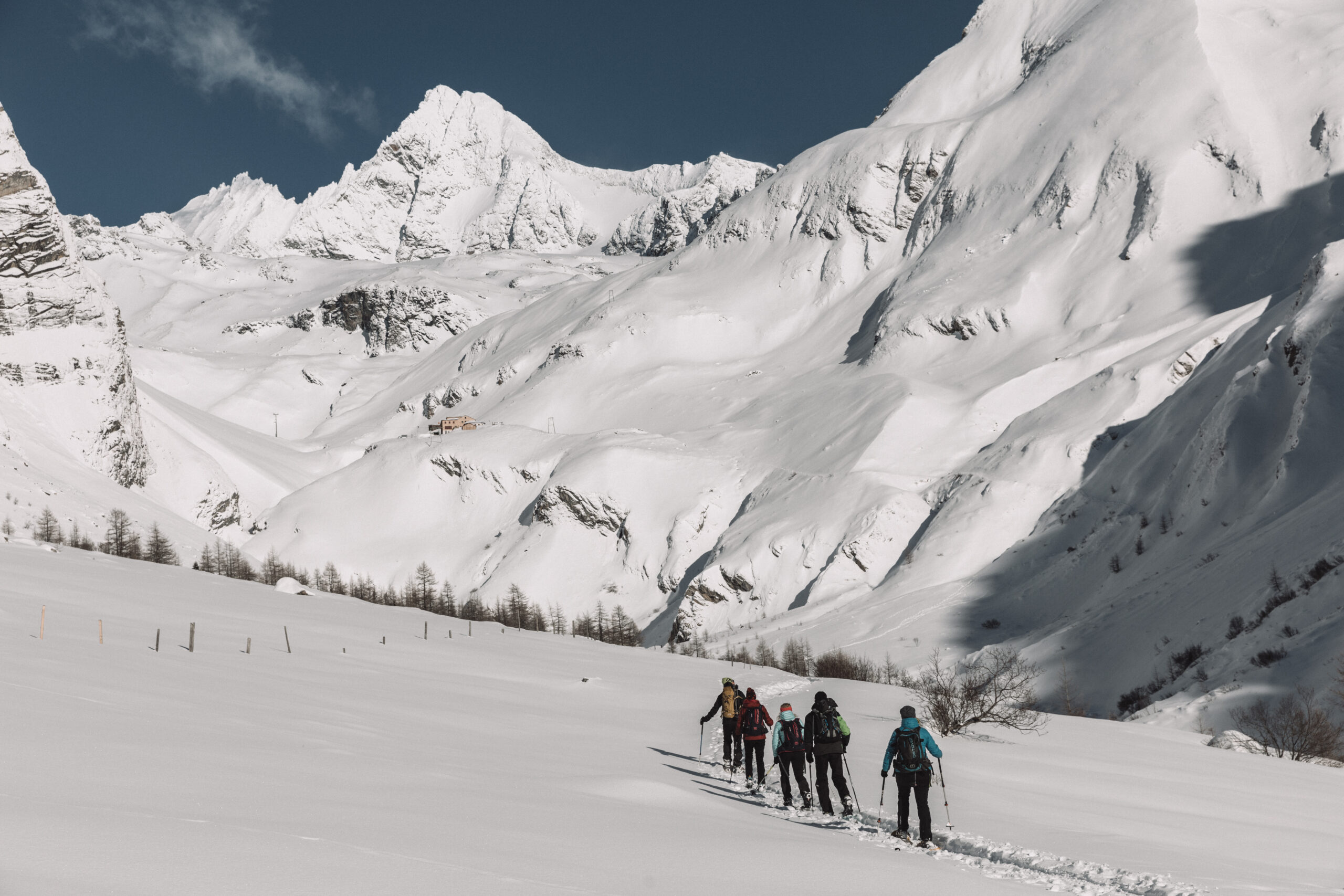 Fünf Personen wandern mit Schneeschuhen durch eine tief verschneite Berglandschaft im Nationalpark Hohe Tauern in Osttirol, mit dem Großglockner im Hintergrund.